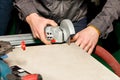 A worker cuts a ceramic-metal plate with a hand-held electric grinder with a diamond disc and dust extraction Royalty Free Stock Photo