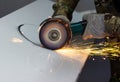 worker cuts a circle in metal with an angle grinder