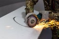 worker cuts a circle in metal with an angle grinder