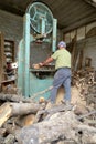 Worker cuts firewood with bandsaw
