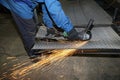 A worker cuts an iron mesh netting with an iron circle. Sparks fly