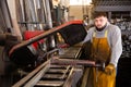 Worker cuts metal profile pipe on a band saw Royalty Free Stock Photo