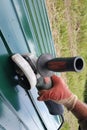 Worker cuts a metal sheet with an angle grinder outdoors in the village Royalty Free Stock Photo
