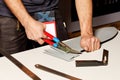 A worker cuts a sheet of roofing iron with metal scissors