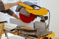 Worker cuts wood baseboard on the power miter saw