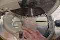 A worker cuts a wooden billet on a floor machine with a circular saw. Concept: woodworking, sawing of materials, violation of safe