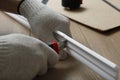 Worker cutting foam crown molding with utility knife at wooden table, closeup Royalty Free Stock Photo