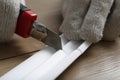 Worker cutting foam crown molding with utility knife at wooden table, closeup Royalty Free Stock Photo