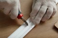 Worker cutting foam crown molding with utility knife at wooden table, closeup Royalty Free Stock Photo