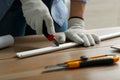 Worker cutting foam crown molding with utility knife at wooden table, closeup Royalty Free Stock Photo