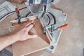 Worker cutting golden moulding on miter saw