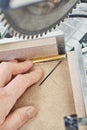 Worker cutting golden moulding on miter saw closeup