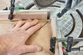 Worker cutting golden moulding on miter saw closeup