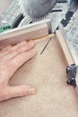 Worker cutting golden moulding on miter saw closeup