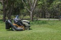 Worker cutting grass lawn mower in green field in garden Royalty Free Stock Photo