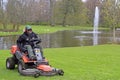Worker is cutting grass on lawn mower in park Royalty Free Stock Photo