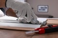 Worker cutting paper with utility knife and ruler at wooden table indoors, closeup Royalty Free Stock Photo