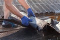 Worker demolishing old shingles to prepare a roof for a new installation. Royalty Free Stock Photo