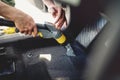 worker, detailer vacuuming carpet of car interior, using steam vacuum