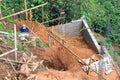 Worker digging holes on a sloping area to put pillars to build house