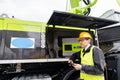 Worker with digital tablet operating construction machine equipment.