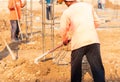 Worker digs soil with spade prepare around pole stucture Royalty Free Stock Photo