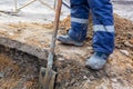 Worker in dirty uniform and shoes with shovel is digging a pit on construction site. Concept of hard work during