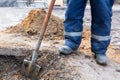 Worker in dirty uniform and shoes with shovel is digging a pit on construction site. Concept of hard work during