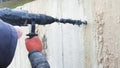 Worker drilling a hole in concrete with a large industrial drill.