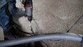 A worker drills into a concrete floor using a drill, close-up. Drilling a floor in concrete. A builder drills into a