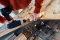 A worker drills a hole in wooden bar with drill