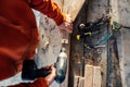 A worker drills a hole in wooden bar with drill