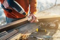 A worker drills a hole in wooden bar with drill