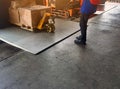 Worker driving forklift loading shipment carton boxes and goods on wooden pallet at loading dock from container truck to warehouse