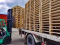 Worker driving forklift to loading and unloading wooden pallets from truck to warehouse cargo storage, shipment in logistics and Royalty Free Stock Photo