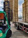 Worker driving forklift to loading and unloading wooden pallets from truck to warehouse cargo storage, shipment in logistics and Royalty Free Stock Photo