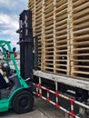 Worker driving forklift to loading and unloading wooden pallets from truck to warehouse cargo storage, shipment in logistics and Royalty Free Stock Photo