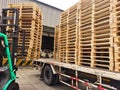 Worker driving forklift truck to unload wooden pallets stack from truck to the cargo warehouse to support shipment for logistics a