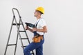 Worker with electric drill on ladder indoors, space for text