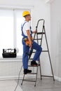 Worker with electric drill on ladder