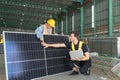 Worker and engineer checking solar panel in warehouse.