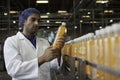 Worker examining orange juice bottle at bottling plant