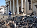 A worker feeding the pigeons on front Romanian Atheneum in Bucharest, May 2018