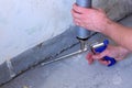 Worker fills crack between wall and cement floor with mounting foam in room.