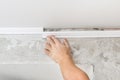 Worker fixes the plastic molding to ceiling. Installation of ceiling cornice.