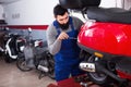 Worker fixing failed scooter in motorcycle workplace Royalty Free Stock Photo