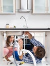 Worker Fixing Sink In Front Of Woman In Kitchen