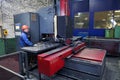 Worker follows the work of machine for drilling steel plates.