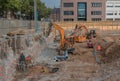 Worker in the foundation trench with construction machinery on the construction site