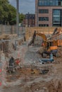 Worker in the foundation trench with construction machinery on the construction site